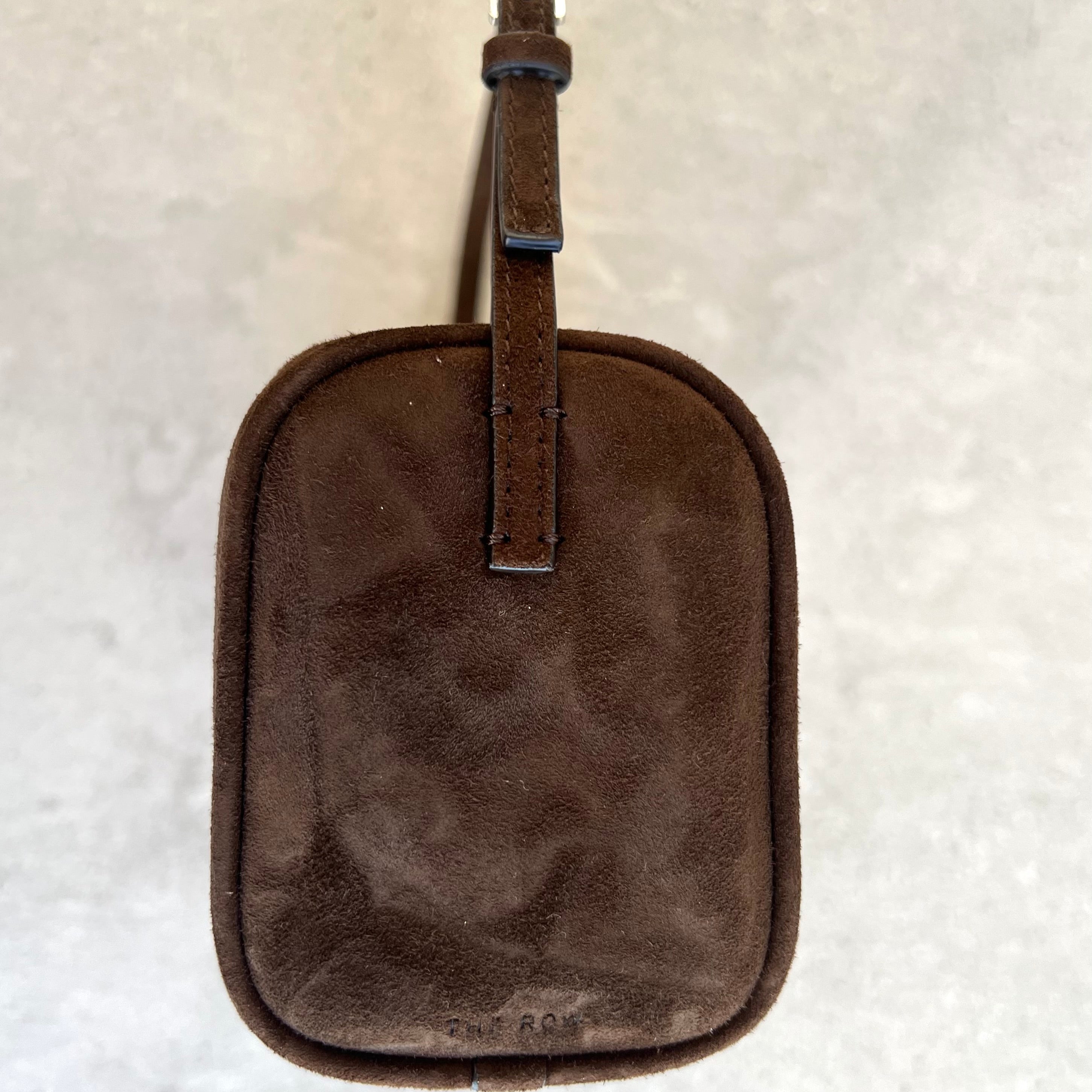 Brown leather luggage tag on a textured beige background