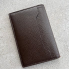Brown leather wallet on a light gray textured surface
