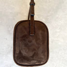 Brown leather luggage tag on a textured beige background